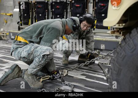 Airmen 1st Class Marcus Downey and Kewei Yu, 43rd Air Mobility Squadron porters, secure a Humvee to the deck of a C-17 Globemaster III during a Deployment Readiness Exercise on Pope Army Airfield Jan. 9, 2017. As part of the exercise, the 43rd AMS brought cargo to the flightline, loaded and then unloaded the aircraft to test the 43rd Air Mobility Operations Group on how they prepare and load cargo for deployment. Stock Photo