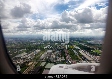 Manufacturing plants and warehouses viewed from a jet window high in the sky. Skyline of building in the background. Stock Photo