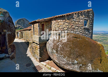 Narrow alley through granite stone houses and huge rocks in historic village Monsanto Stock Photo