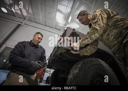 U.S. Army Sgt. 1st Class Shawn Blackford, a wheeled vehicle mechanic senior instructor with the New Jersey Army National Guard's Regional Training Support-Maintenance, teaches a local police officer how to change a Humvee light on Joint Base McGuire-Dix-Lakehurst, N.J., Dec. 18, 2018. The Humvees were acquired by local police via the Law Enforcement Support Office (LESO) program at no cost. The vehicles are used for equipment transport, high-water rescue, and inclement weather. Stock Photo