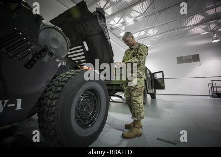 U.S. Army Sgt. 1st Class Russell Huth, a wheeled vehicle mechanic senior instructor with the New Jersey Army National Guard's Regional Training Support-Maintenance, replaces the light on a Rutherford Police Department Humvee on Joint Base McGuire-Dix-Lakehurst, N.J., Dec. 18, 2018. The Humvees were acquired by local police via the Law Enforcement Support Office (LESO) program at no cost. The vehicles are used for equipment transport, high-water rescue, and inclement weather. Stock Photo