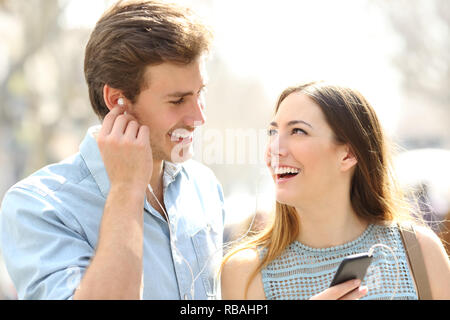 Happy romantic couple sharing online music dating in the street Stock Photo