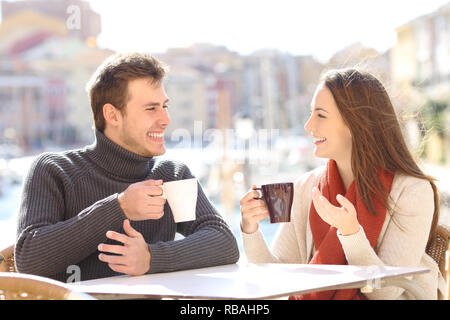 Happy couple talking on vacation drinking coffee in a restaurant Stock Photo