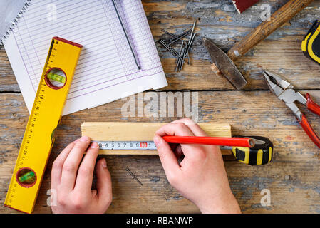 Carpenter working with crafting tools in his workshop. Top view of man's hands measuring on working desk. Stock Photo