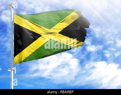 National flag of Jamaica on a flagpole in front of blue sky. Stock Photo