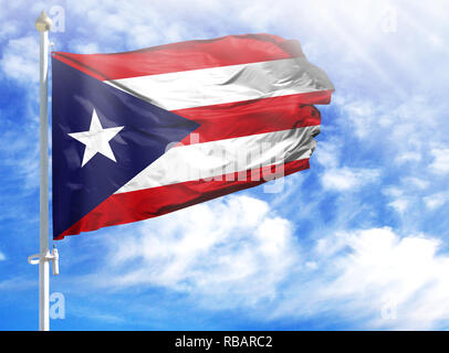 National flag of Puerto Rico on a flagpole in front of blue sky. Stock Photo