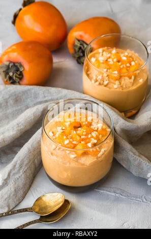 Smoothie with persimmon and cashew nuts in glasses on gray concrete background Stock Photo