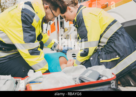 Paramedics performing first aid at ambulance Stock Photo