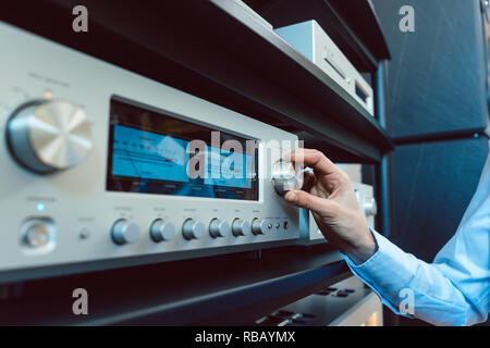 Hand of woman turning up volume of Hi-Fi amplifier Stock Photo
