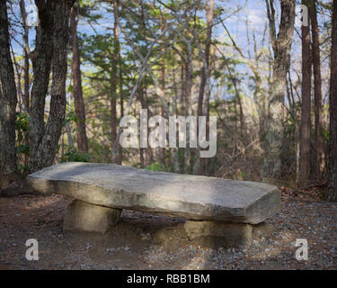 Rock bench along trail to upper cascade waterfall at Hanging Rock State Park, NC. Stone bench rest area along path Stock Photo