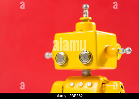 Portrait of a Cute, yellow, handmade robot on a red background. Stock Photo