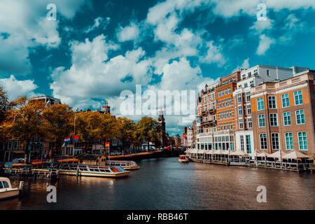 City view of Amsterdam with cruise boats and typical brick houses on sunny day with Vibrant fluffy clouds. Stock Photo