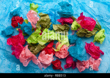 Crumpled colorful tissue paper on a blue tissue paper background Stock Photo