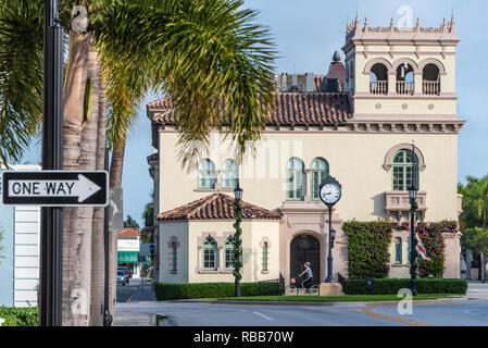 Woman riding bicycle in front of the historic Town Hall in Palm Beach, Florida. (USA) Stock Photo