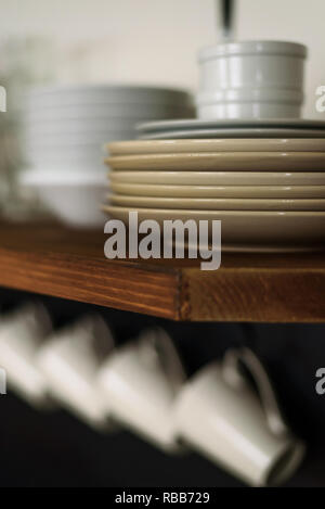 Close-up of plates and cups on open wooden shelf in modern kitchen Stock Photo