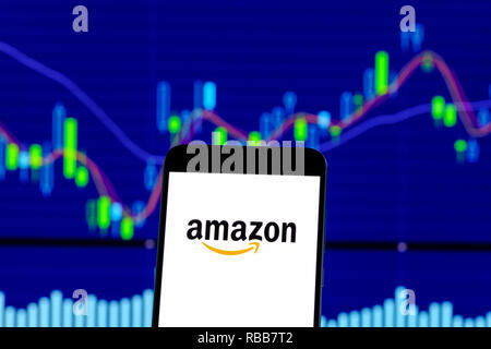 amazon logo is seen on an smartphone over stock chart Stock Photo
