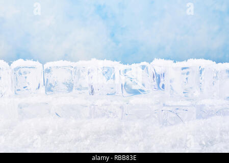 Ice cubes with snow over blue background. Copy space for text or design element. Stock Photo