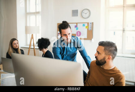 Group of young businesspeople with laptop working in a modern office. Stock Photo