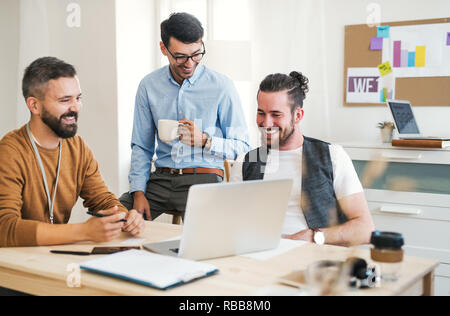 Group of young businessmen with laptop working in a modern office. Stock Photo