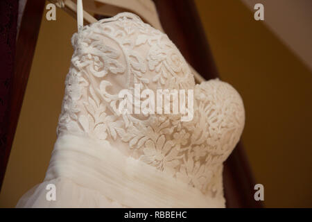 close up of a brides dress on her wedding day, showing the top section of the white wedding dress and embroidery on it with waistband too Stock Photo