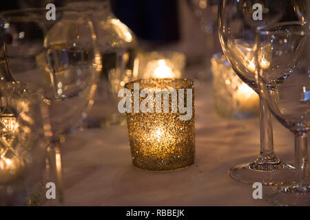 tea light candles in small sparkly candle holder vases on a wedding day table ready for the entrance of the bride and groom on their wedding day Stock Photo