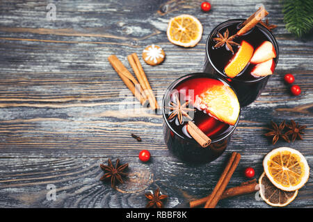 Christmas mulled wine with spices, orange slices, cinnamon sticks and fir branches on wooden table. Traditional drink on winter holiday. Rustic style. Stock Photo