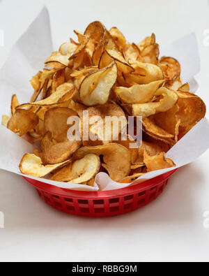 Red basket of hand made  fried potato chips isolated on white background. Stock Photo