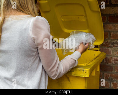 Frau wirft etwas in gelbe Tonne Stock Photo