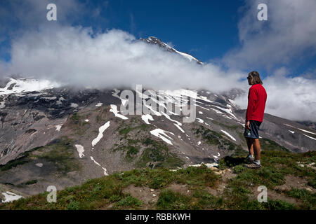 WA15685-00...WASHINGTON - Hiker viewing Mount Rainier from the summit of Pyramid Peak in Mount Rainier National Park. Stock Photo