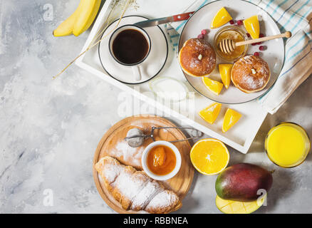 Breakfast served with coffee, orange juice, croissants, donuts and fruits on white tray. Top view Stock Photo