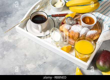 Breakfast served with coffee, orange juice, croissants, donuts and fruits on white tray. Stock Photo