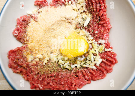 minced beef with egg, breadcrumbs and spices in a bowl from above, cooking preparation for meatballs, selected focus Stock Photo