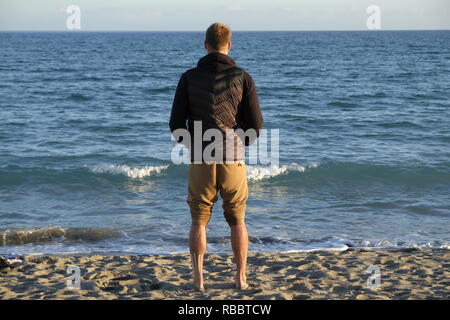 a boy looking panorama over the sea horizon in the beach - winter season at sunset Stock Photo