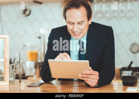 Making research. Handsome man in black suite holding tablet searching information in internet Stock Photo