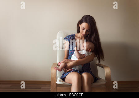 Young mother holding her newborn child chair copy space love care concept bonding time Stock Photo