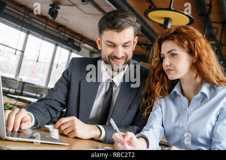 Man and woman having business lunch at restaurant sitting at table businessman browsing laptop looking at businesswoman taking notes smiling happy clo Stock Photo
