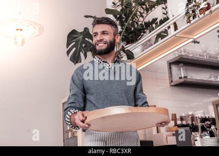 Positive cheerful man bringing order to his customers Stock Photo