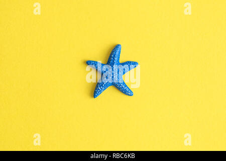 Blue starfish isolated on yellow background minimal summer creative concept. Stock Photo