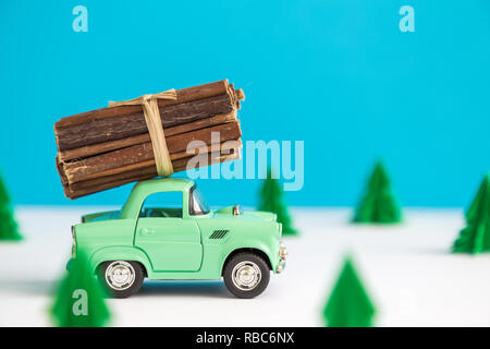 Car toy with logs on roof on snowy road minimal creative winter travel concept. Stock Photo