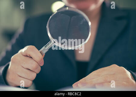 Business corruption audit inspection concept, female inspector using magnifying glass Stock Photo