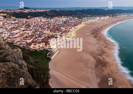Nazaré beach, in Portugal, at dusk with lights on, seen from the Sítio's viewpoint. Stock Photo