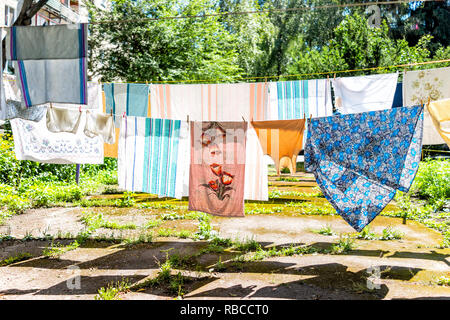 Many hanging clothes in summer garden with colorful shirts drying on rack in Ukraine or Russia by Soviet apartment buildings Stock Photo