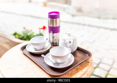Closeup of two white cups of coffee or tea in breakfast brunch outdoor cafe restaurant outside table with sunny day, thermos and teapot pot Stock Photo