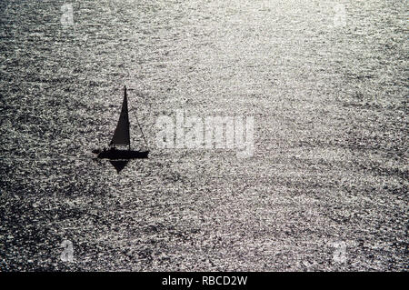 Small sailing boat on shining sea. Stock Photo