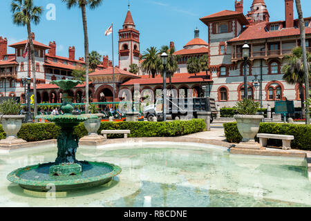 St. Augustine, USA - May 10, 2018: Flagler College with Florida architecture, famous statue in historic city, water fountain and trolley tour guide tr Stock Photo