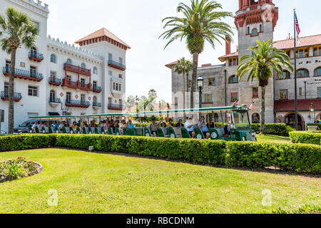 St. Augustine, USA - May 10, 2018: Flagler College with Florida architecture, famous statue in historic city, grass lawn and trolley tour guide tram Stock Photo