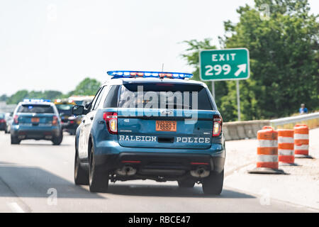 Raleigh, USA - May 13, 2018: Highway road in North Carolina with closeup of traffic police car with siren by exit and sign Stock Photo