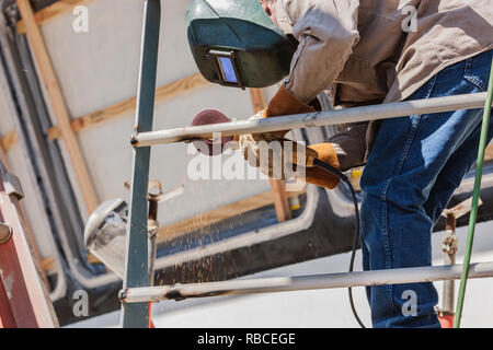 View From Below Of Welder Working With Grinder Stock Photo
