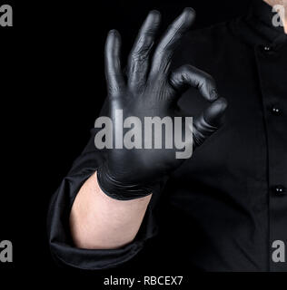 male chef's hand in black latex gloves and black uniform shows gesture like, all is well Stock Photo