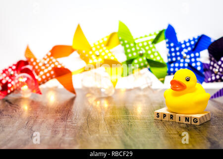 Colorful rainbow pinwheels and yellow duck on a wooden board for fun cheerful background for Spring, Summer, Party, Baby Stock Photo